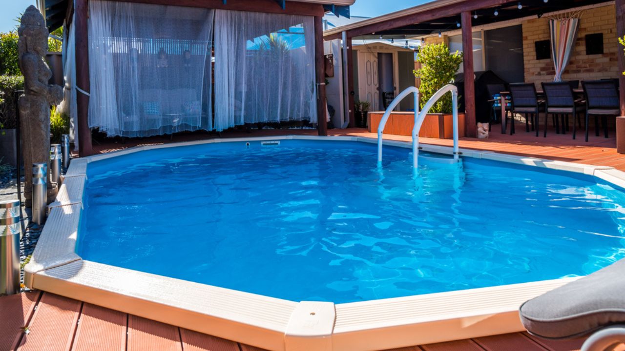 Above ground pool sunken below ground and surrounded by decking.
