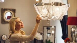 Beautiful mature blond haired woman checking out gorgeous crystal chandelier at the home decor store copyspace furniture supermarket coziness apartment shopping buying retail purchasing.