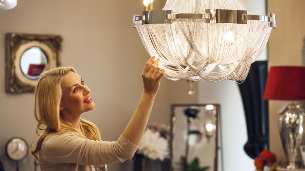 Beautiful mature blond haired woman checking out gorgeous crystal chandelier at the home decor store copyspace furniture supermarket coziness apartment shopping buying retail purchasing.