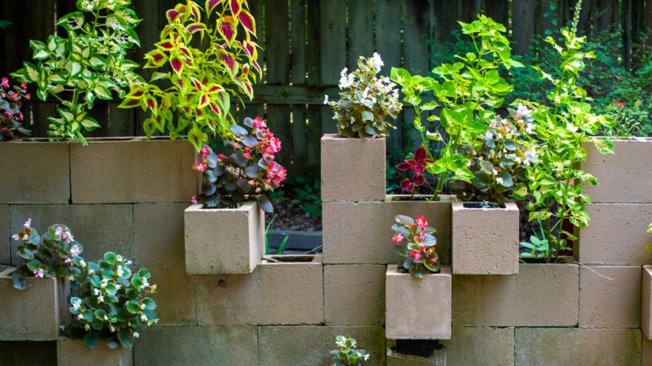 Cement cinder blocks make a unique stair step plant display. A variety of plants fill in the blocks creating an eye appealing rustic nature scene.