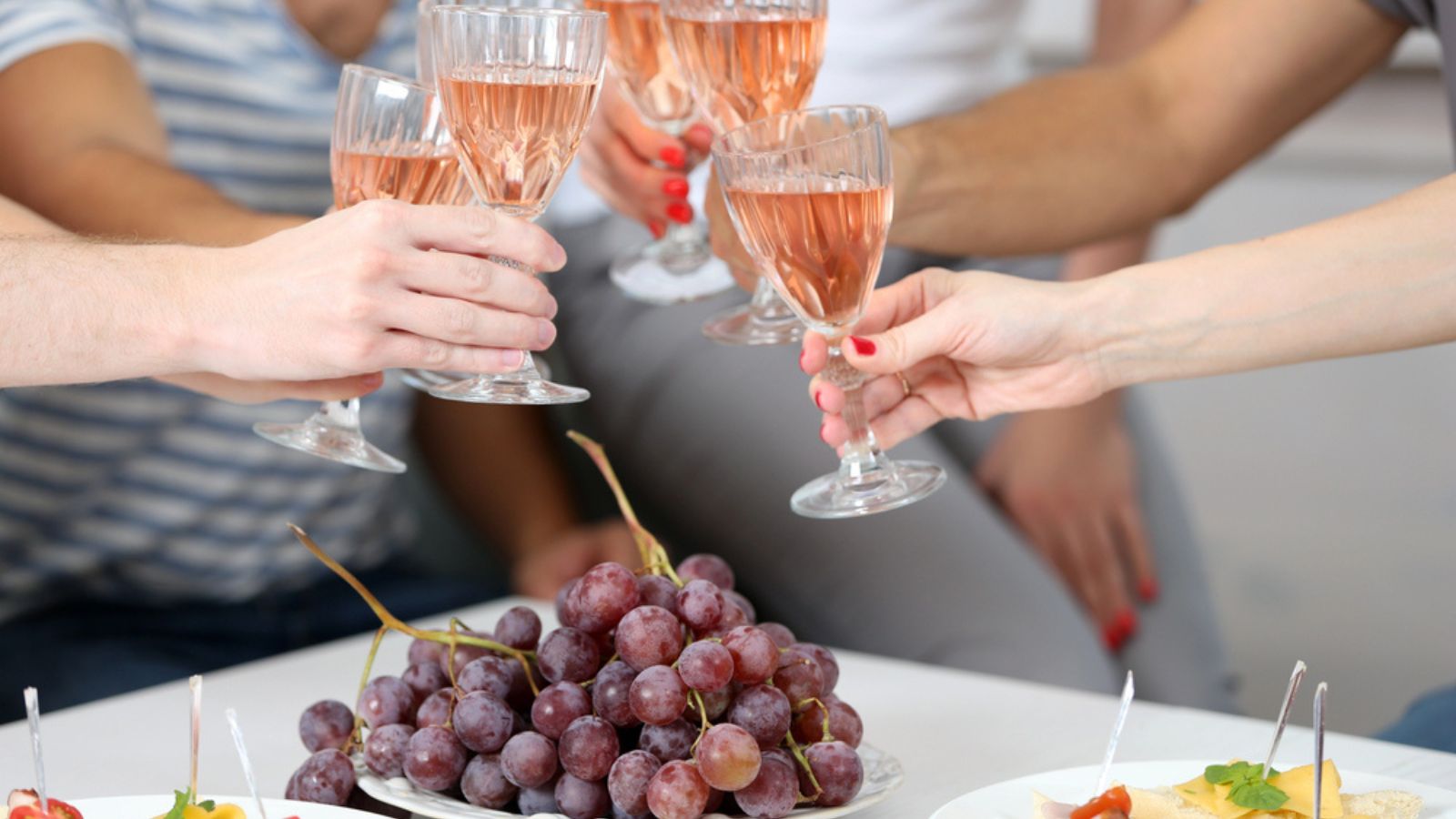 Friends hands with glasses of wine and snacks, close up
