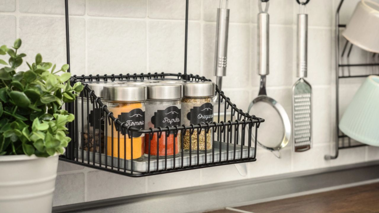 Glass jars with different spices in wire basket on kitchen