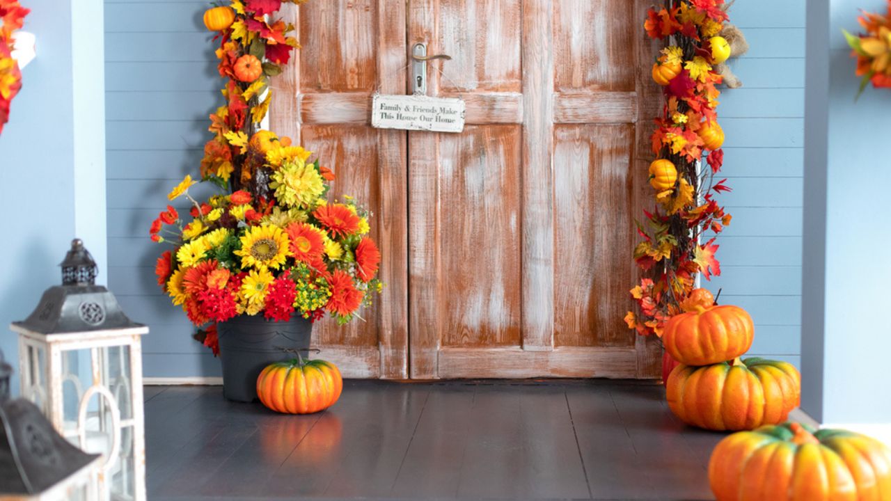 Halloween composition design home with yellow fall leaves and flowers. Cozy wooden porch of house with pumpkins