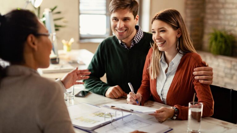 Happy Couple Signing Mortgage Contract While Having Meeting with Real Estate Agent.