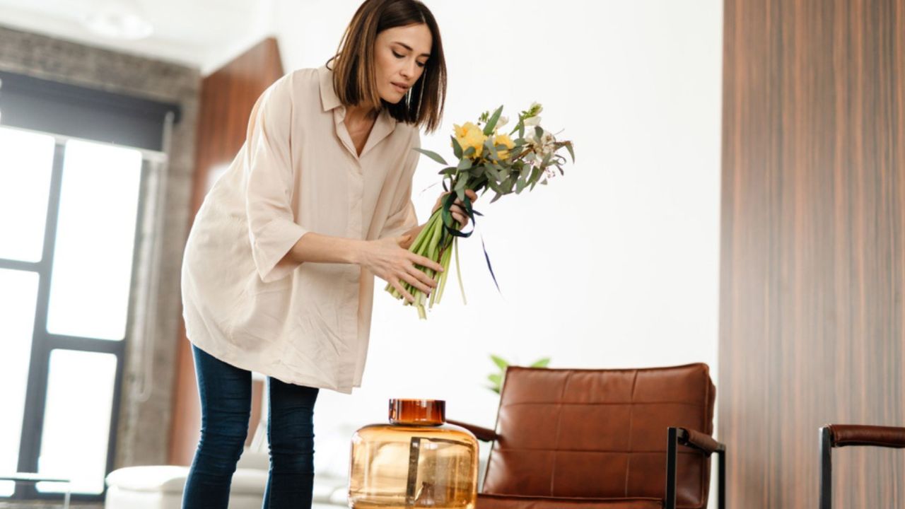 Middle Aged Woman Decorating Living Room with Flower Bouquet in a Vase - 1