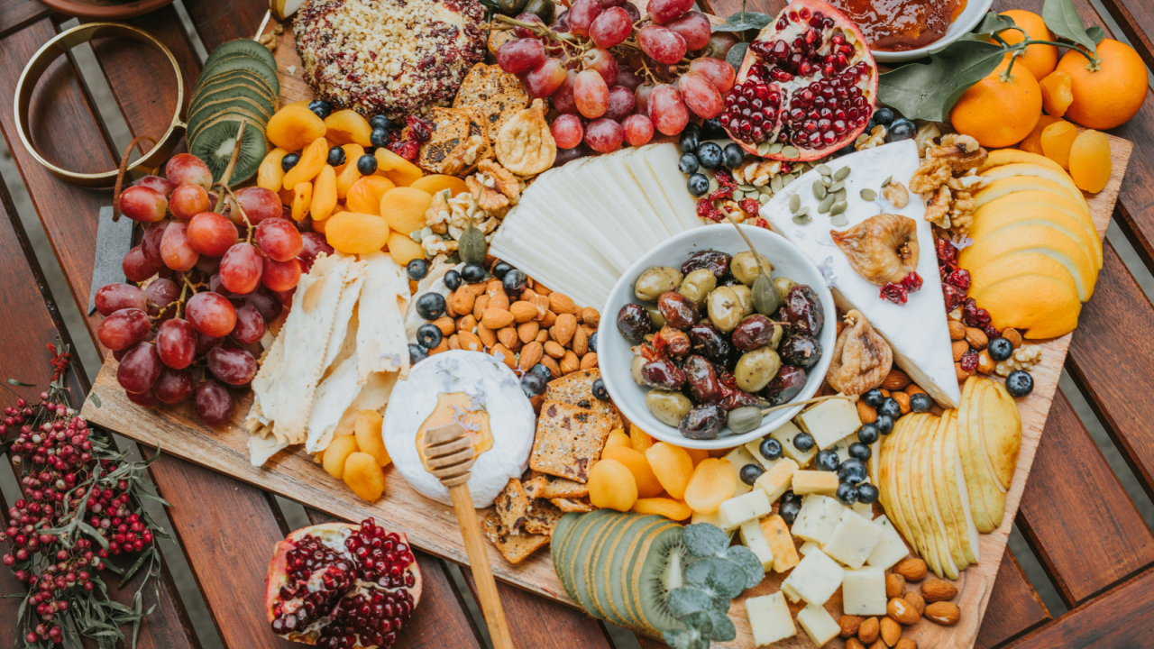 Artisan charcuterie boards kiwi grapes jam pomegranate olives cheese apricot kiwi orange almond food on the table