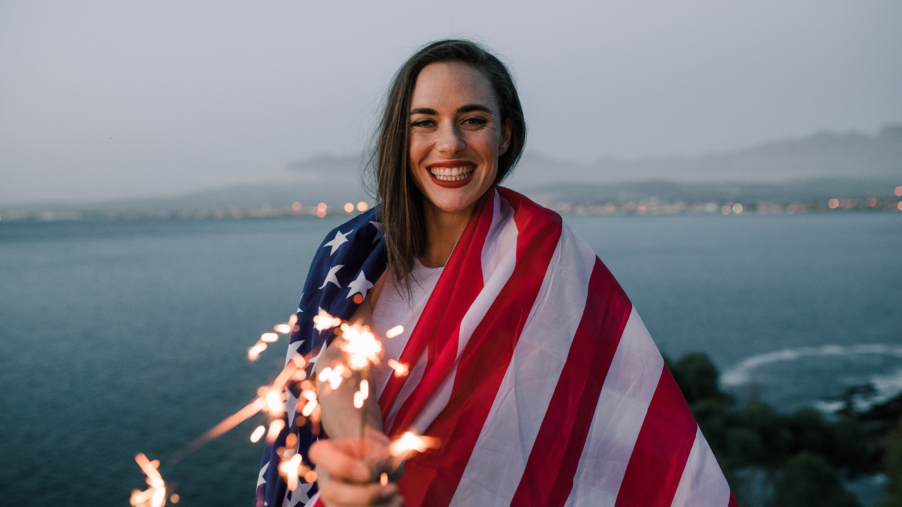 woman holding sparklers and an american flag 4th of july