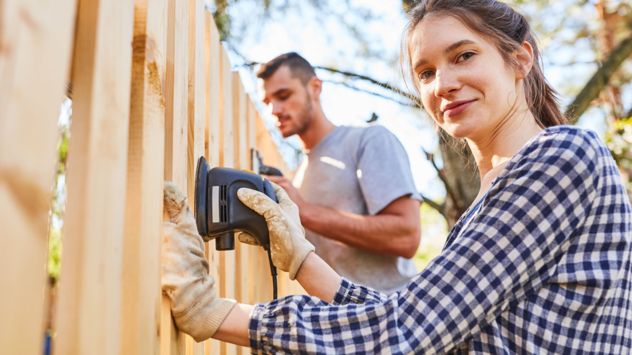 woman and man building a fence sanding