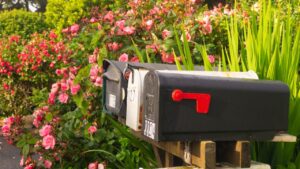 White picket fence and cute mail box covered in beautiful bright red and pink blooming flowers