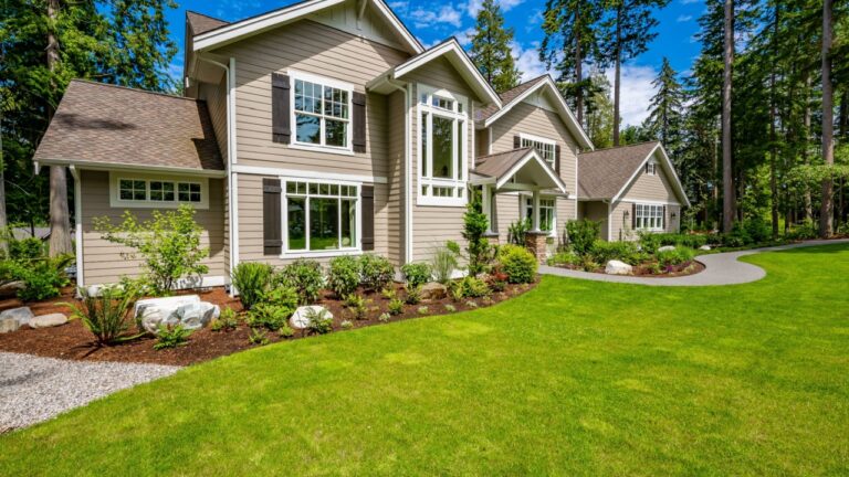 Beautiful custom built craftsman style home three car garage with wooden doors lush landscaping with spring foliage and shadows dappling the yard