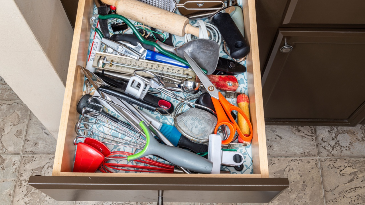 A genuine kitchen junk drawer almost overflowing with genuine kitchen junk.