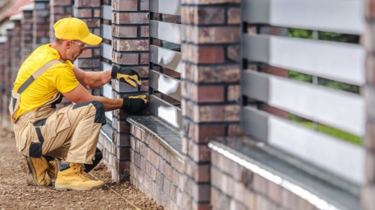 Residential Decorative Brick and Aluminium Panels Fence Building. Fencing Worker Performing Final Checks.