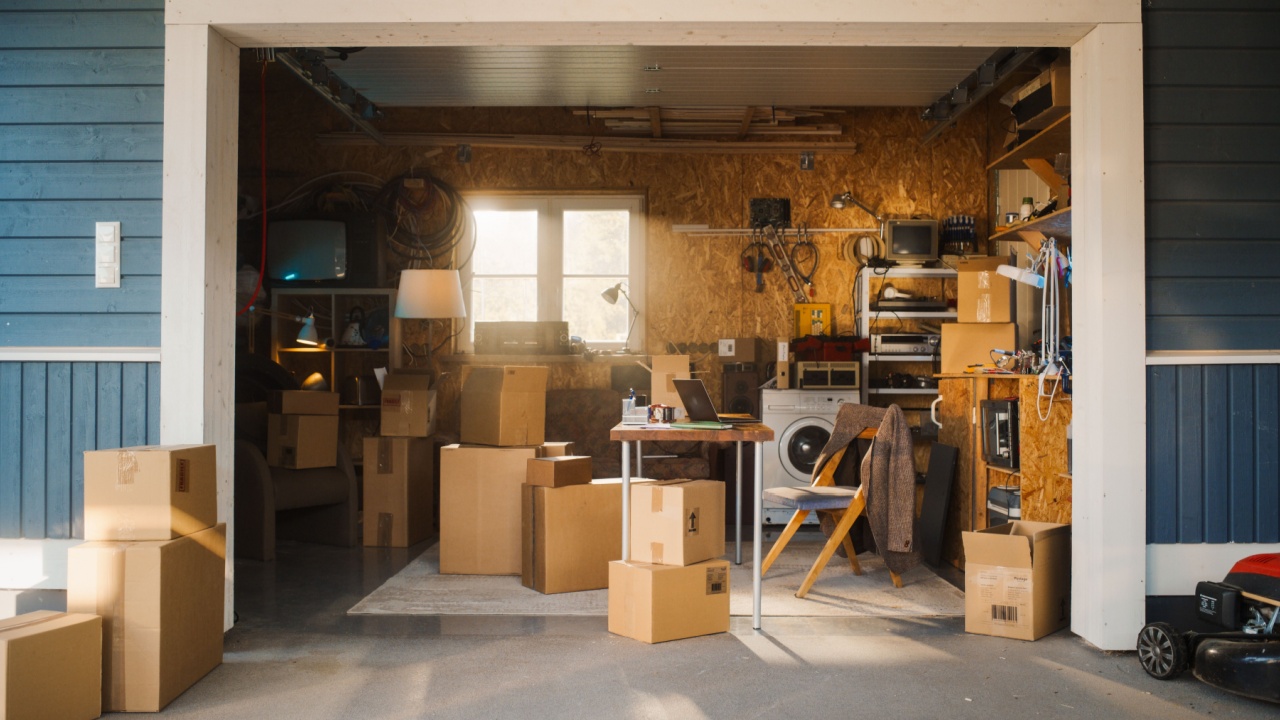 Establishing Shot Of Small Business Owners Empty Workplace With Laptop In Garage. Cardboard Boxes With Products Packed For Shipping to Clients Laying Around.