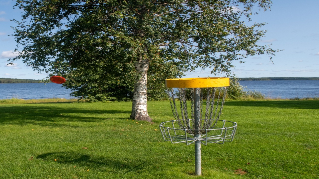 Woman throwing frisbee disc in the disc golf field.