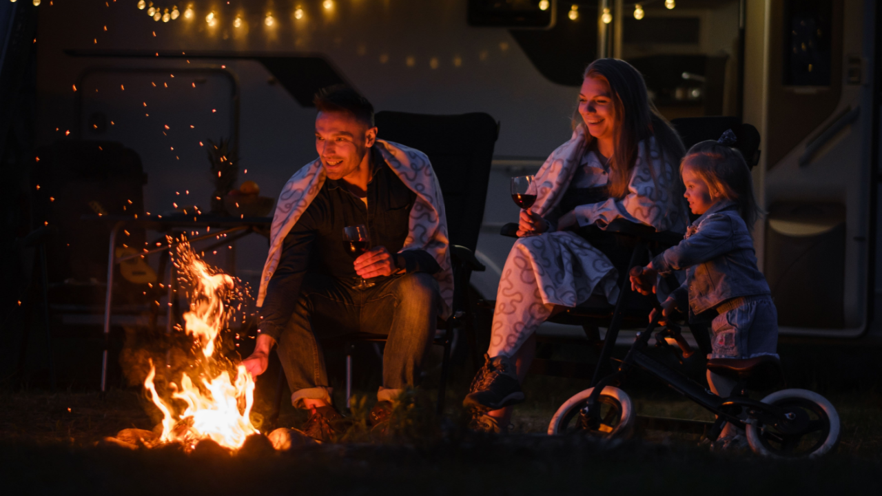 family in blankets around a backyard campfire with lights