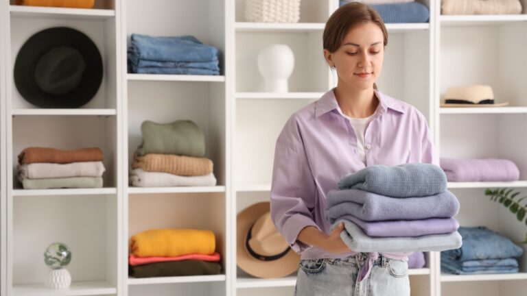 Young woman holding warm sweaters in dressing room