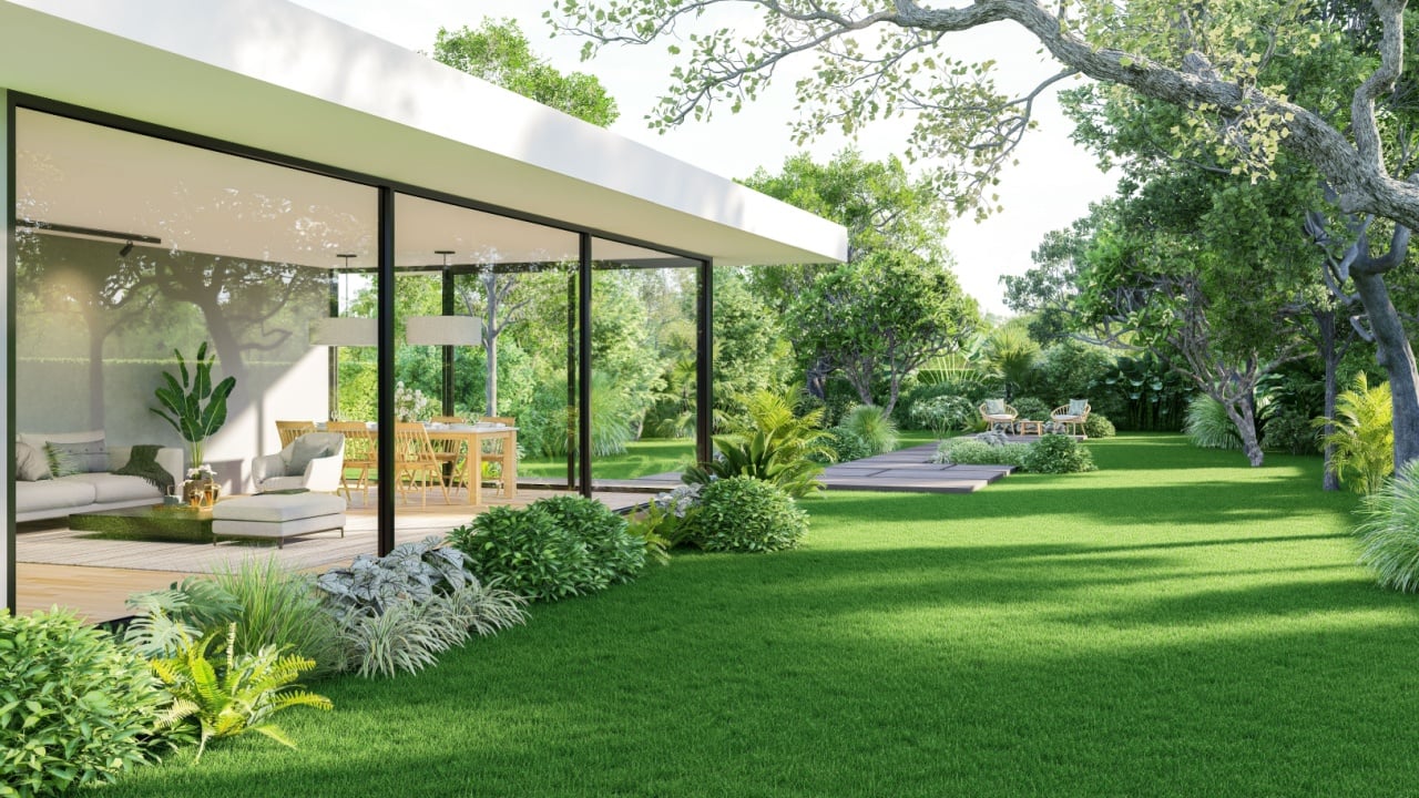 Empty green lawn of modern style house with tropical green garden background.