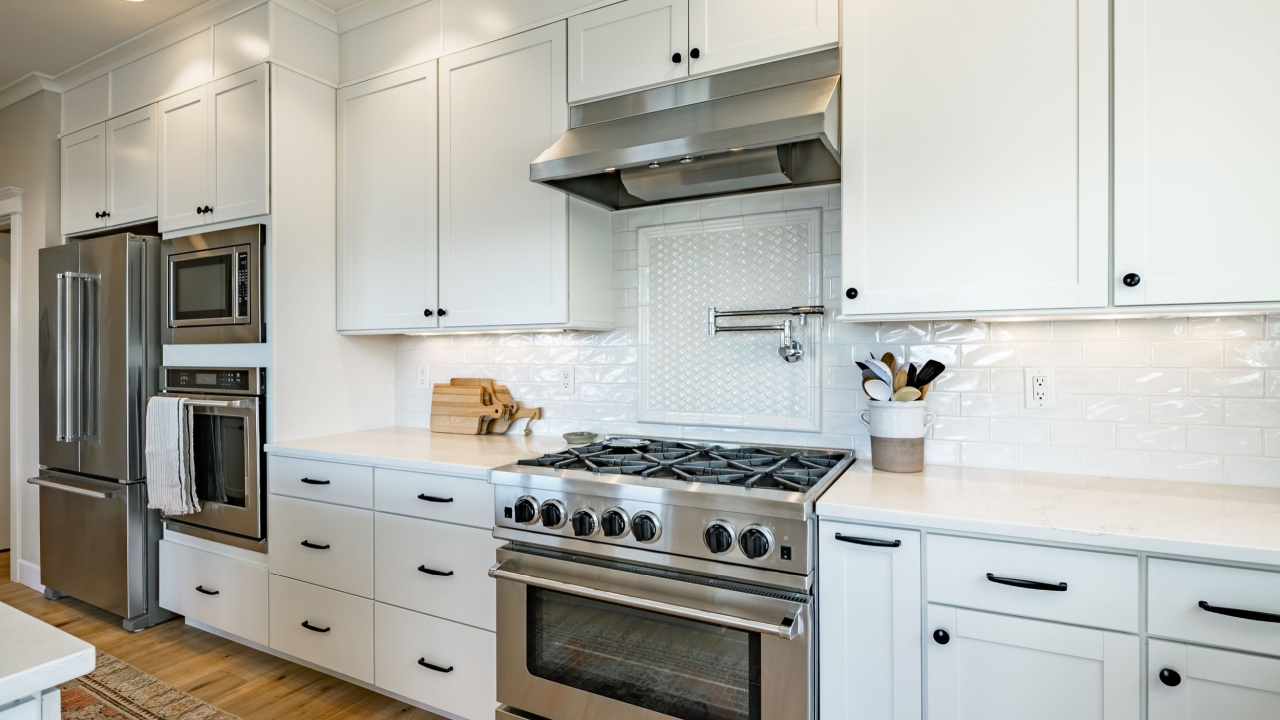 cabinetry, a large kitchen island with a light-colored countertop, and stainless steel appliances creates a bright, clean, and airy atmosphere.