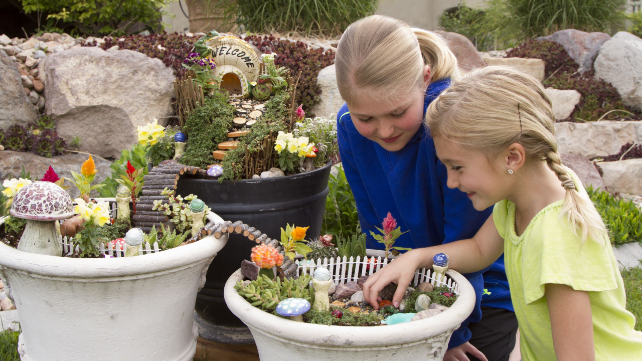 Two young girls helping to make fairy garden in a flower pot