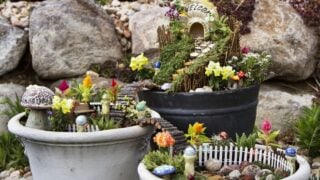 Fairy garden in a flower pot with walking path, wooden bridges and a fairy house.