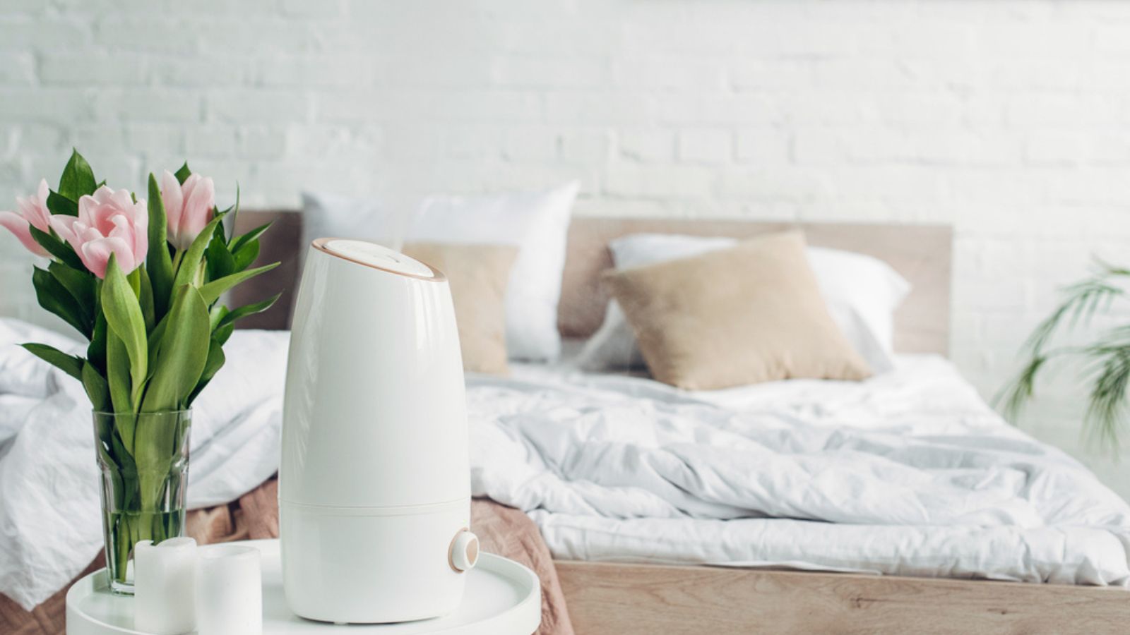 White ultrasonic purifier, tulips and candles on table in bedroom