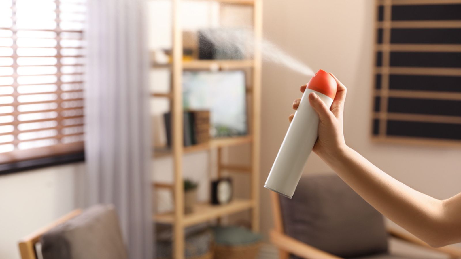 Woman spraying air freshener at home, closeup