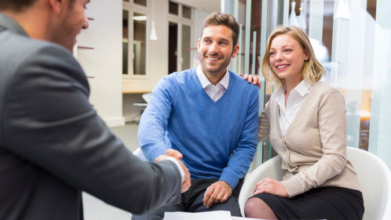 Young Couple Shaking Hand Real-Estate Agent in Agency Office