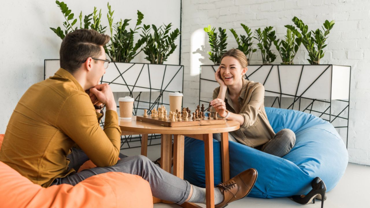 Young happy friends playing chess while sitting on beanbags