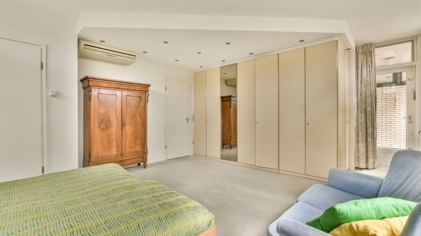 A bedroom with a bed, chair and closets in the room