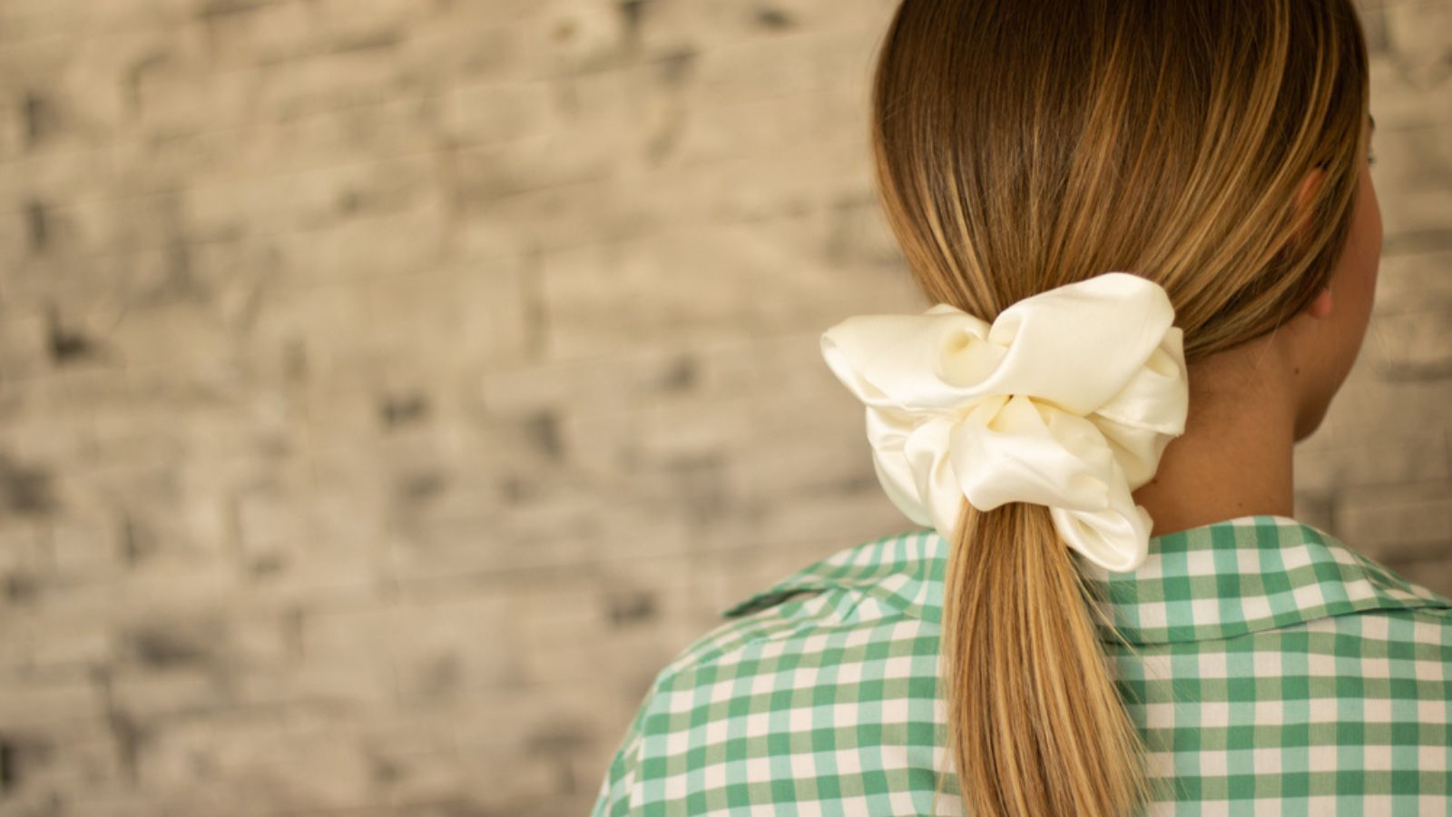 A shallow focus of long dirty blonde hair tied with a scrunchie