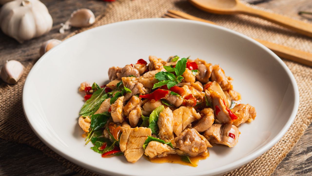 Stir fried chicken with basil and chili in white plate on wooden background. Thai Food Stir fried chicken with basil and chili in white plate on wooden background. Thai Food