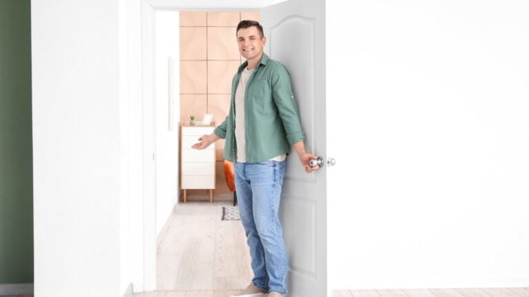 Happy man inviting guest at his new home