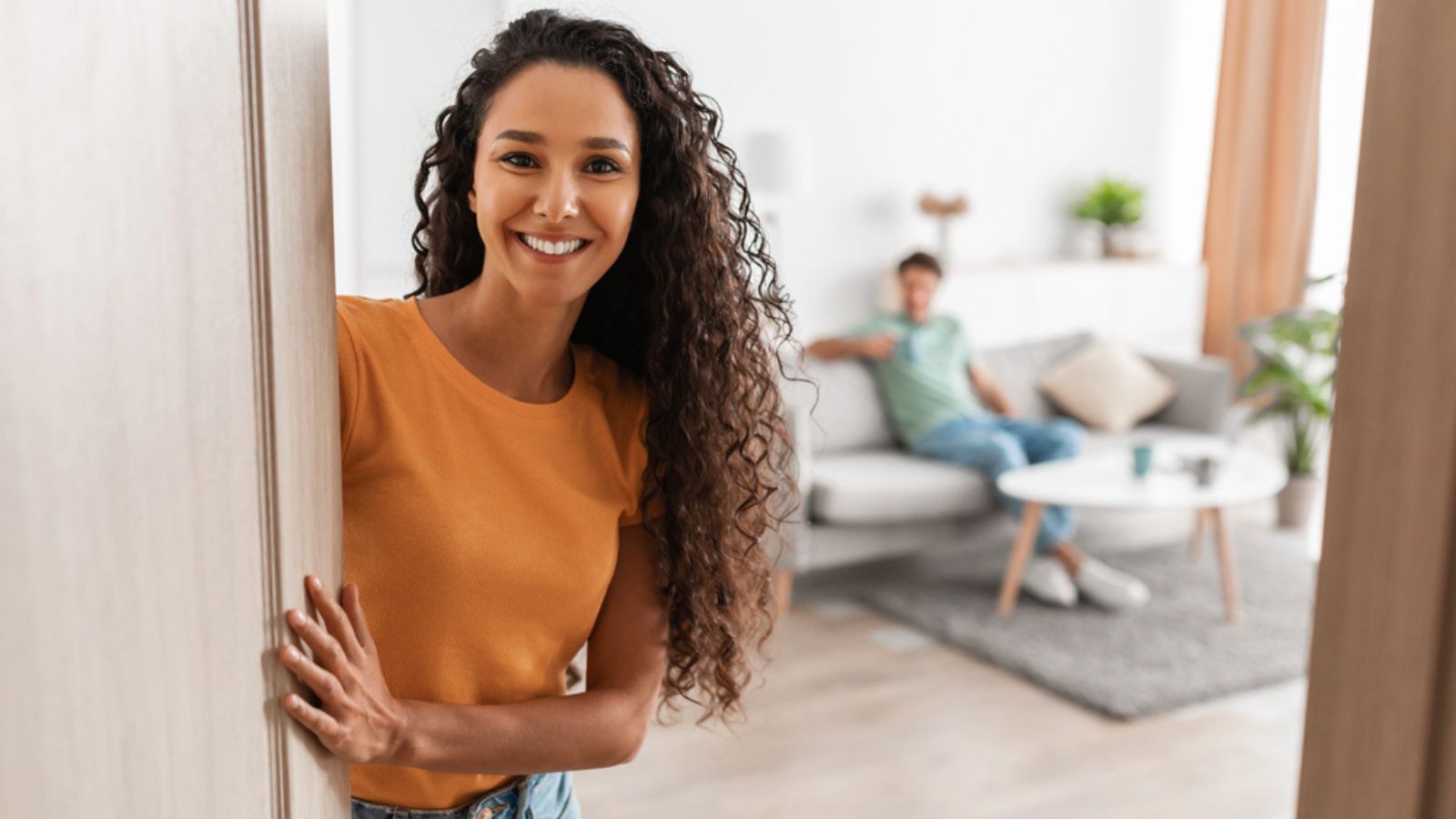 Happy young couple inviting guests people to enter home