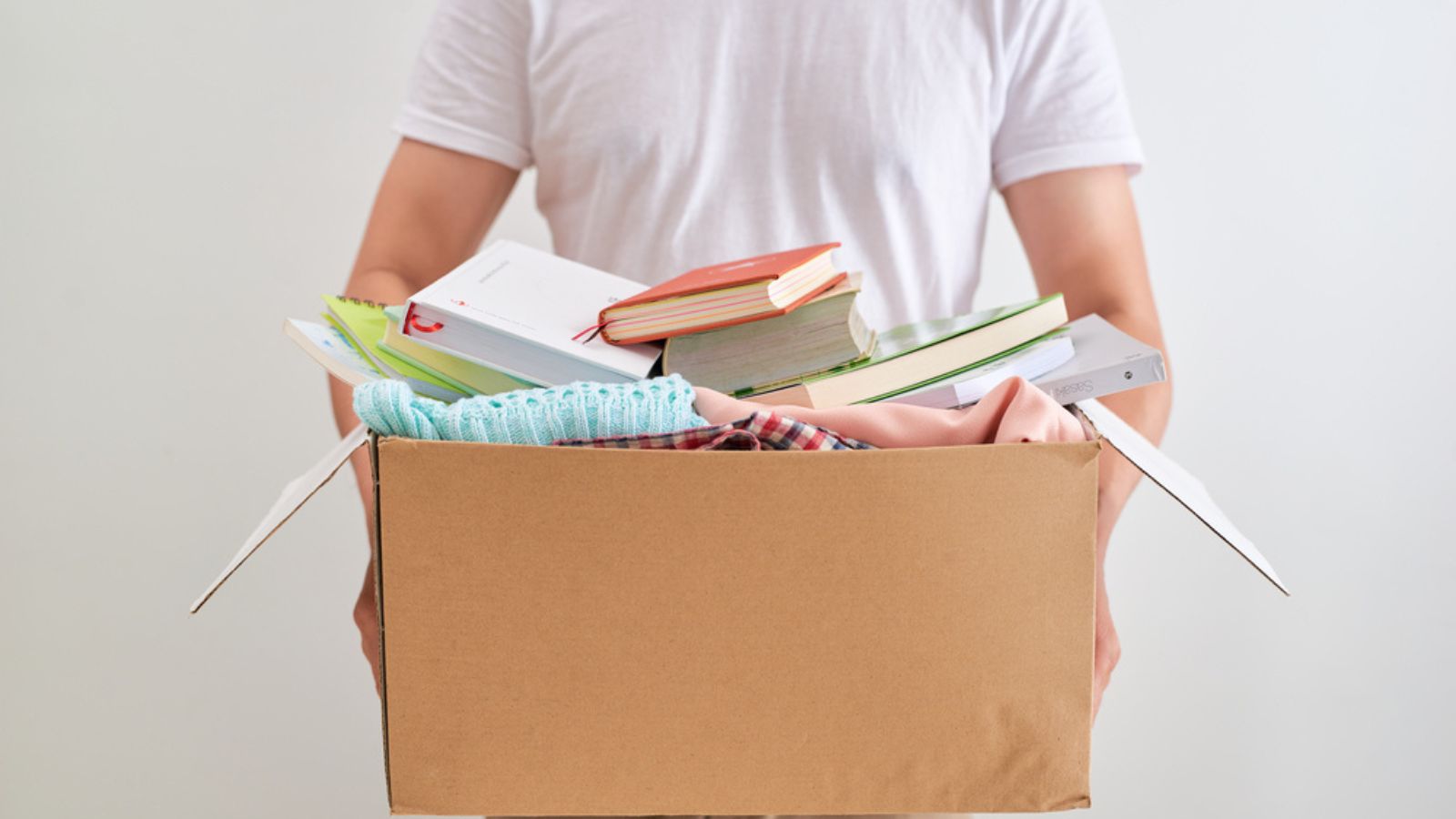 Man holding donate box with books and clothes