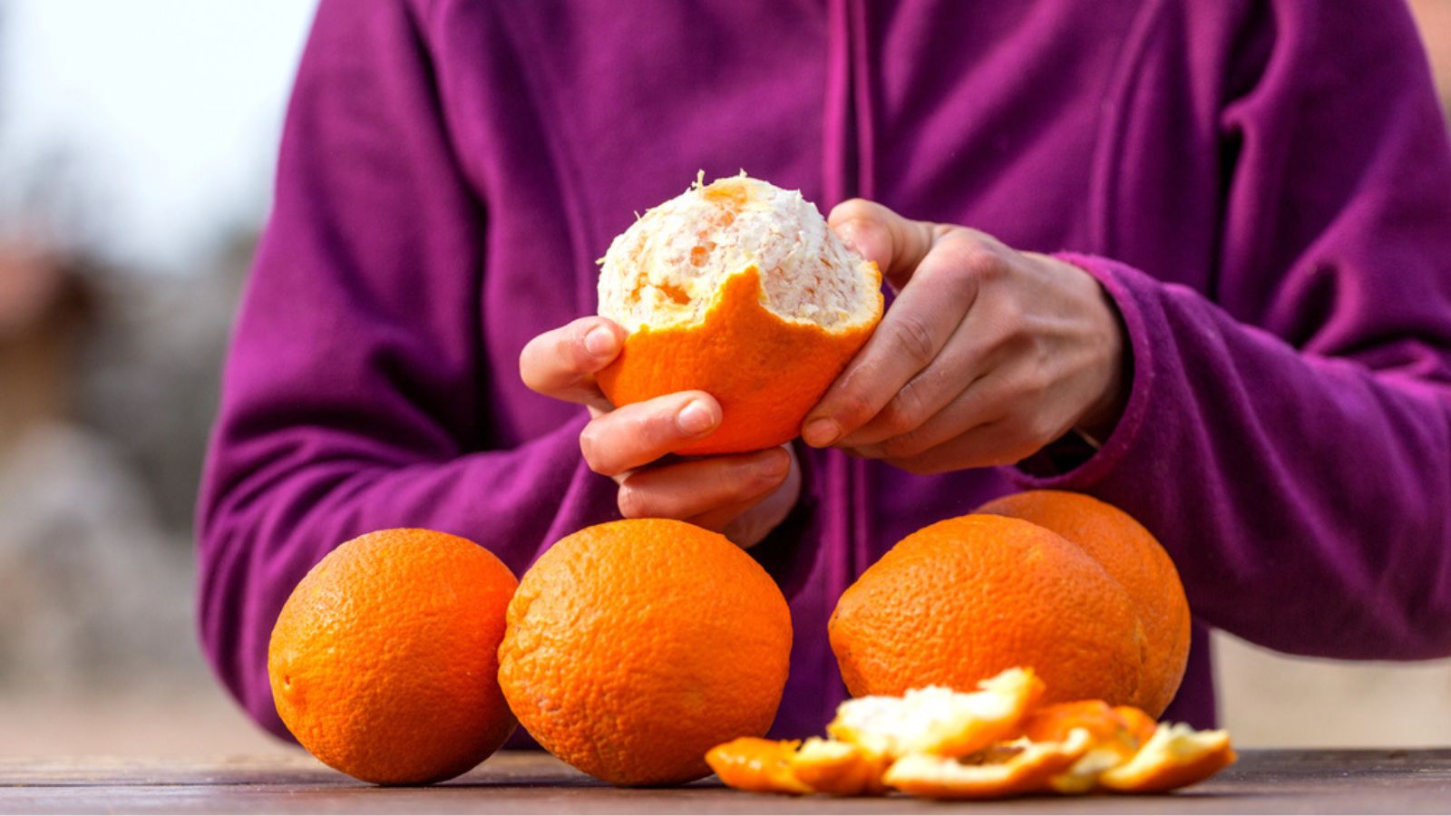 Orange in female hands closeup. Peeled citrus fruits.Woman peels oranges from peel.