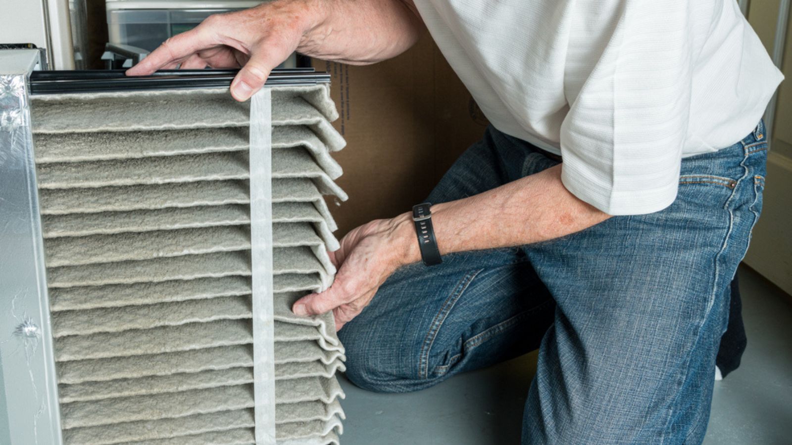 Senior man changing a dirty air filter in a HVAC Furnace