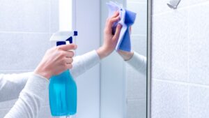 Cleaning and polish mirror with rag and spray in bathroom at home. Housekeeping and cleaning service. Clean house, cleanliness