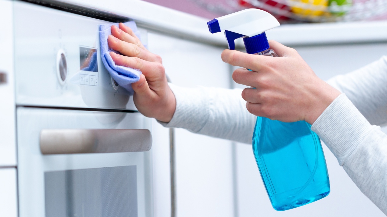 Dusting and polish gas stove using cleaning products in kitchen at home. Housekeeping. Clean house, cleanliness