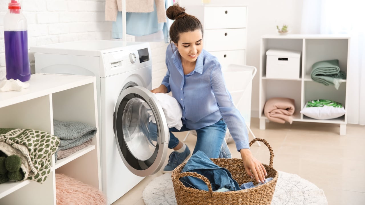 Beautiful young woman doing laundry at home