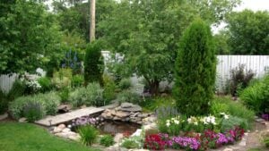 A scenic view of a well manicured back yard flower garden and pond.