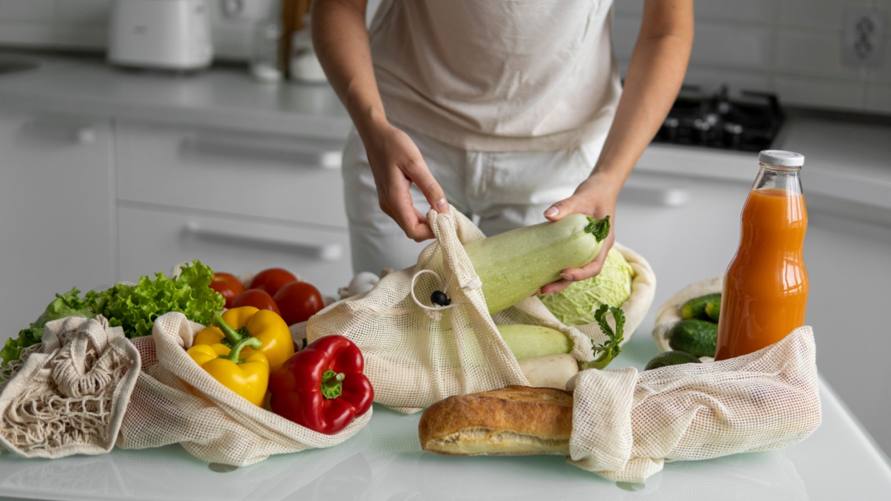 Woman's hand, holding a reusable grocery bag with vegetables on a kitchen at home and takes zucchini out. Zero waste and plastic free concept. Mesh cotton shopper with vegetables. Ecology.