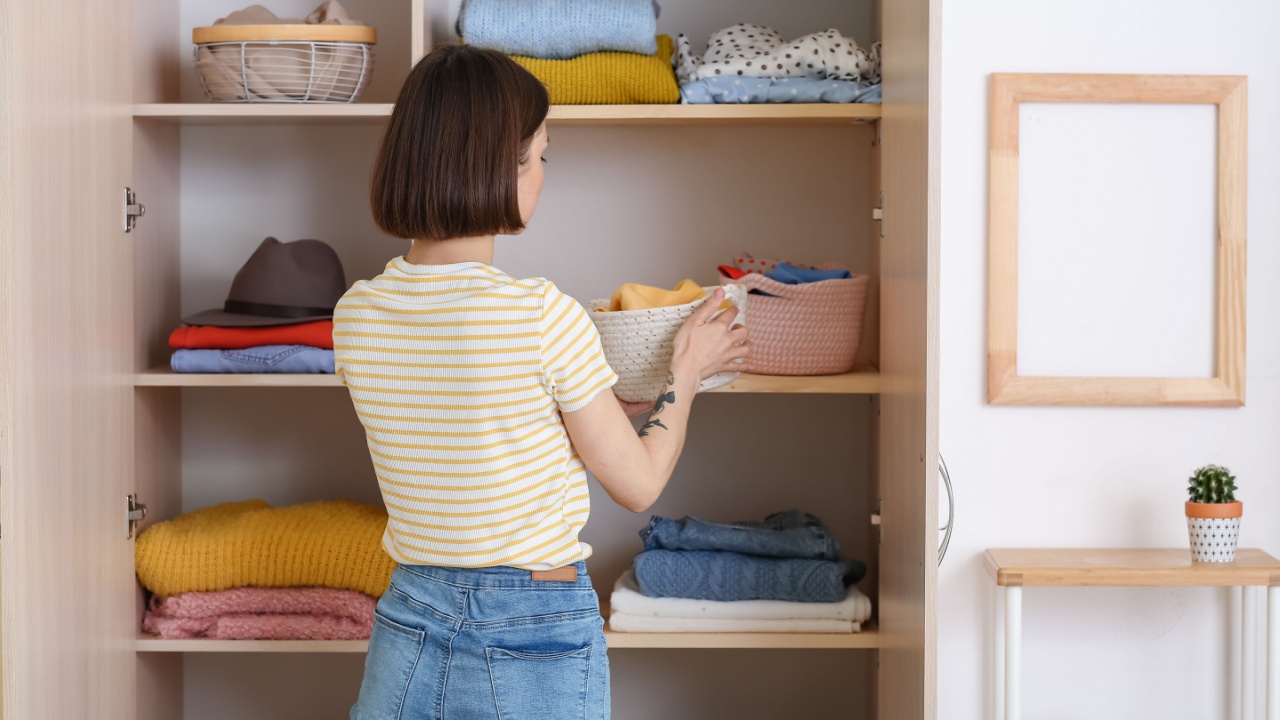 Young woman organizing clothes at wardrobe
