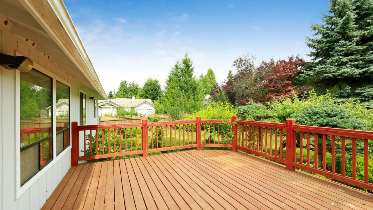 One story house with wooden walkout deck overlooking backyard garden