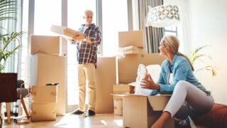 Real estate, property and a senior couple moving house while packing boxes together in their home. Box, investment and retirement with old people unpacking in the living room of their new apartment