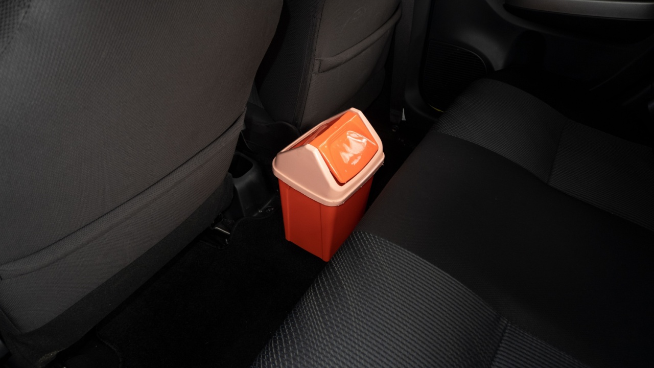 selective focus on the orange trash can between the passenger seats of the car. under exposure