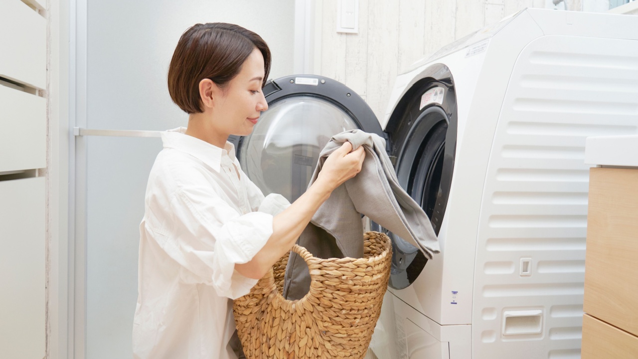Asian middle aged woman washing clothes in a washing machine