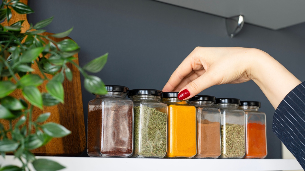 Cropped hand holding jar of spices on kitchen.
