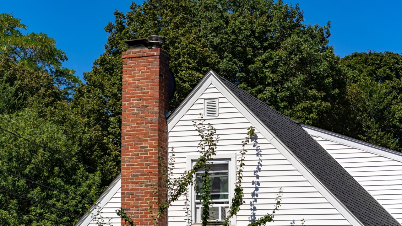 Home facade with white siding and brick chimney in Brighton, Massachusetts, USA