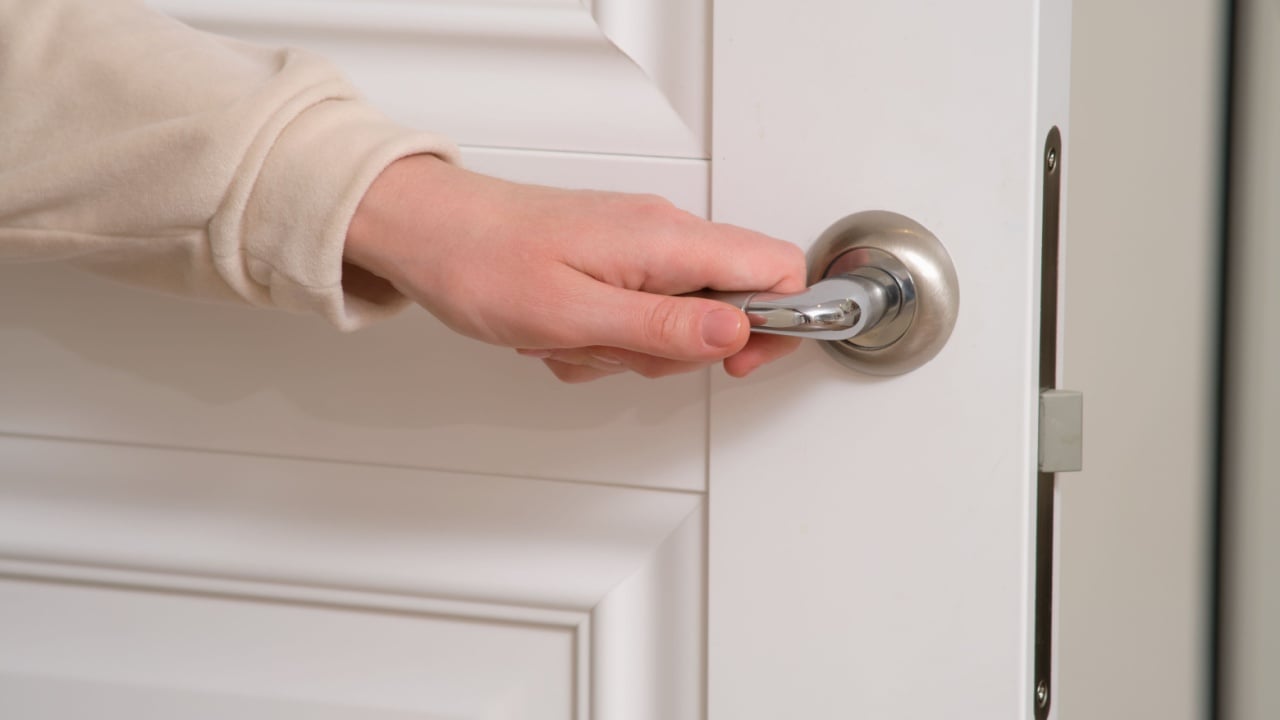 A woman hand opens the door by the handle, close-up