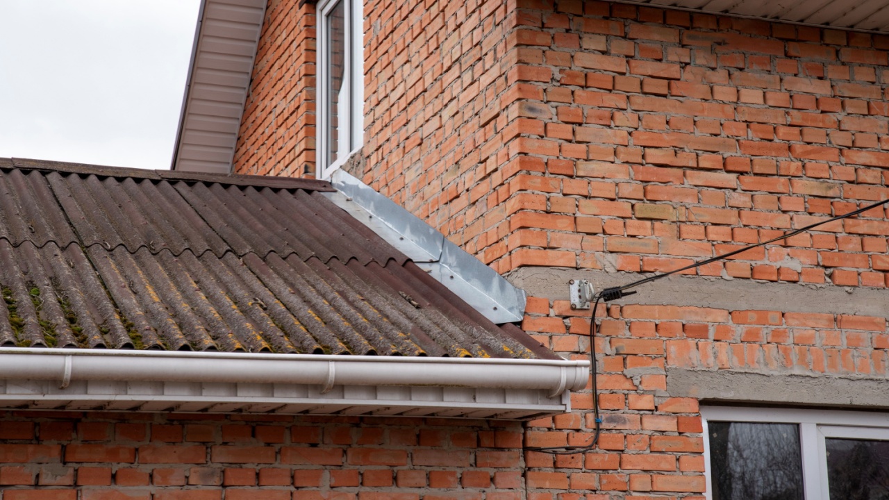 Corner of a brick house with a wavy roof and a metal apron